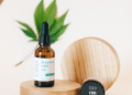 Hemp-derived CBD oil and topical product containers displayed with hemp leaves on a wooden platform