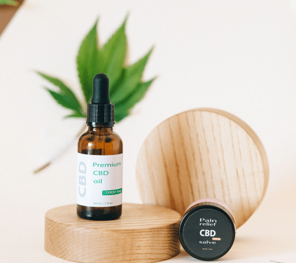 Hemp-derived CBD oil and topical product containers displayed with hemp leaves on a wooden platform