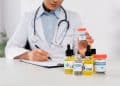 partial view of african american doctor with stethoscope holding bottle with medical cannabis