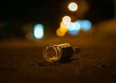 A selective focus shot of empty bottle of alcohol thrown in the middle of street on bokeh background