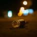 A selective focus shot of empty bottle of alcohol thrown in the middle of street on bokeh background