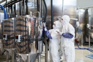 Wide angle view at two workers wearing protective suits while inspecting production at modern chemical plant, copy space