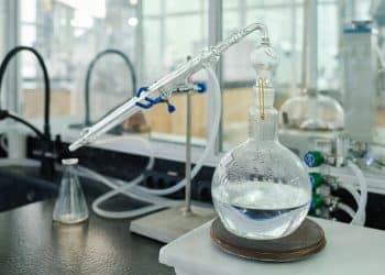 Process of vaporization of liquid chemical substance in order to get new solid one on workplace of modern scientist during experiment